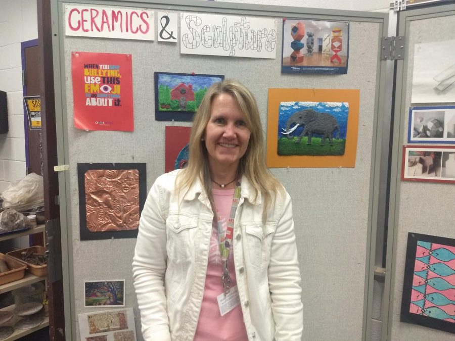 Ms. Schutte stands in front of student artwork.