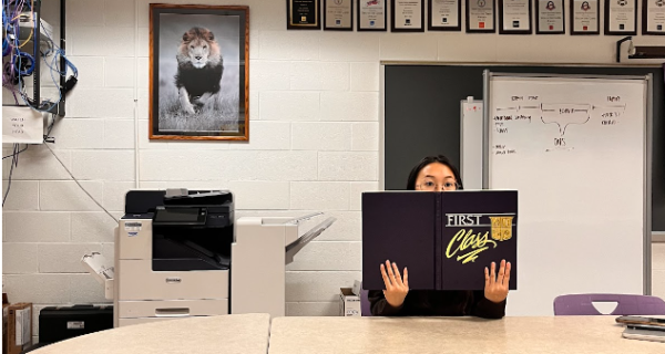 Lincey Chu,the senior editor of the yearbook,holds the first class book.